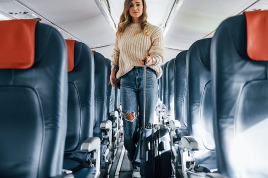 Front view. Young female passanger in casual clothes is in the plane.