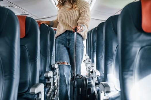 Front view. Young female passanger in casual clothes is in the plane.