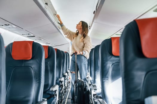 Front view. Young female passanger in casual clothes is in the plane.