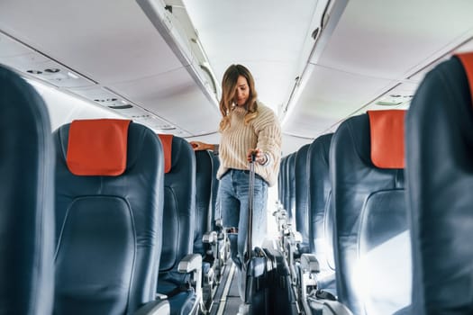 Front view. Young female passanger in casual clothes is in the plane.