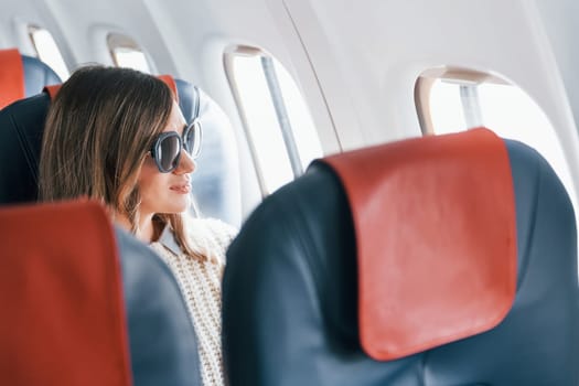 Conception of vaccation. Young female passanger in casual clothes is in the plane.