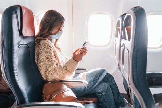 Young tourist. Female passanger in casual clothes is in the plane.