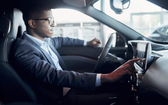 Vehicle interior. Young african american businessman in black suit is in the automobile.