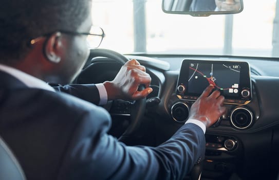 Vehicle interior. Young african american businessman in black suit is in the automobile.