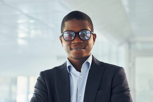 Young african american businessman in black suit is indoors.