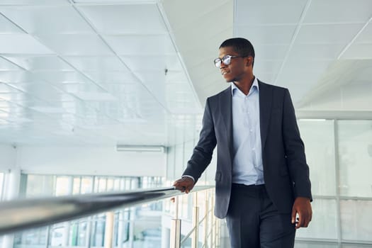 Young african american businessman in black suit is indoors.