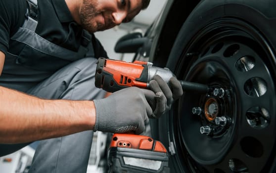 Modern vehicle. Man in uniform is working in the autosalon at daytime.