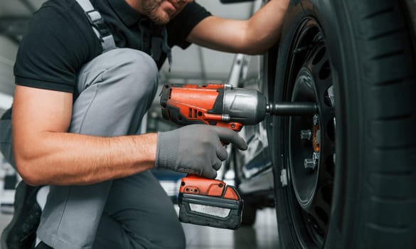 Modern vehicle. Man in uniform is working in the autosalon at daytime.
