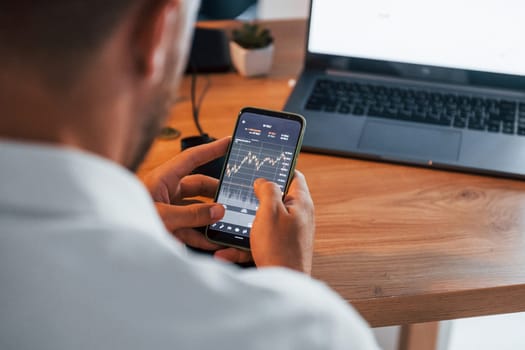 Graphs and diagrams. Young businessman in formal clothes is in office with multiple screens.