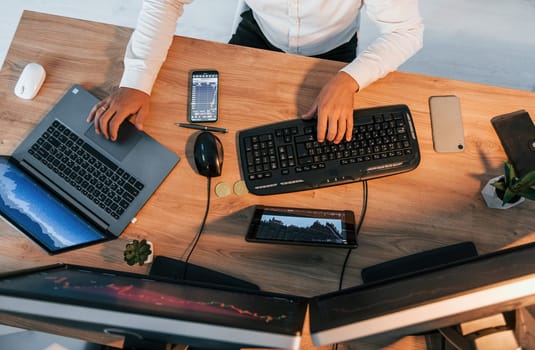 Close up view. Young businessman in formal clothes is in office with multiple screens.