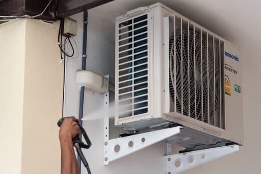 Bangkok, Thailand - July 22, 2017 : Unidentified worker to cleaning coil cooler of air conditioner by water for clean a dust on the wall in customer home when maintenance service