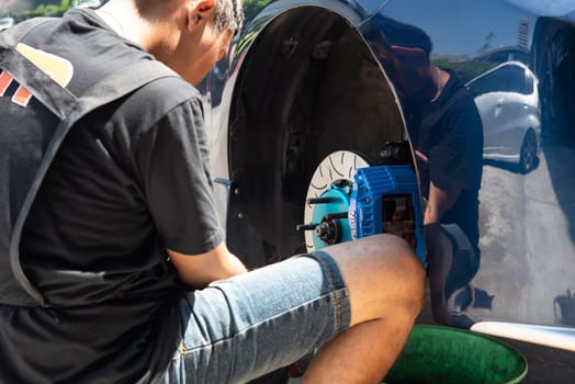 Bangkok, Thailand - March 6, 2021 : Unidentified car mechanic or serviceman disassembly and checking a disc brake and asbestos brake pads for fix and repair problem at car garage or repair shop