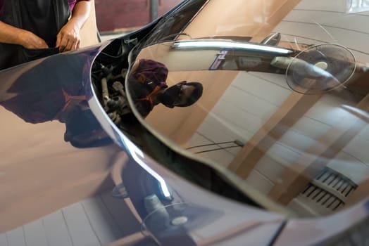 Bangkok, Thailand - July 5, 2021 : Unidentified car mechanic or serviceman install and fitting a new windscreen or windshield for fix and repair problem at car garage or repair shop