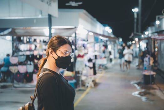 Beautiful asian woman (LGBTQ) natural makeup wear fashion yellow leather clothes with glasses posing with food or drink at thai street food, market or restaurant outdoor fashion style