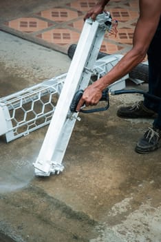 Worker to cleaning coil cooler of air conditioner by water for clean a dust on the wall in customer home when maintenance service