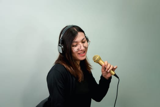 Beautiful asian woman (LGBTQ) is a singer. She enjoying sing a song or karaoke in music studio with microphone condenser and headphones for fun or voice creative