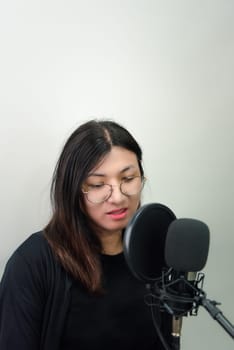 Beautiful asian woman (LGBTQ) is a singer. She enjoying sing a song or karaoke in music studio with microphone condenser and headphones for fun or voice creative