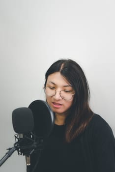 Beautiful asian woman (LGBTQ) is a singer. She enjoying sing a song or karaoke in music studio with microphone condenser and headphones for fun or voice creative