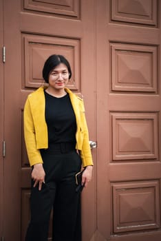 Beautiful asian woman (LGBTQ) natural makeup wear fashion yellow leather clothes with glasses posing at old town and vintage building outdoor fashion style