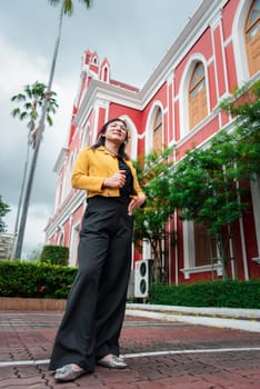 Beautiful asian woman (LGBTQ) natural makeup wear fashion yellow leather clothes with glasses posing at old town and vintage building outdoor fashion style