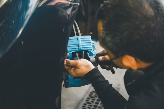 Car mechanic or serviceman disassembly and checking a disc brake and asbestos brake pads for fix and repair problem at car garage or repair shop