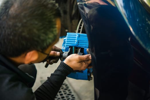 Car mechanic or serviceman disassembly and checking a disc brake and asbestos brake pads for fix and repair problem at car garage or repair shop