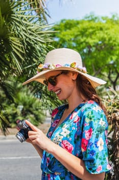 Vertical portrait of young happy woman on holidays looking at pictures in camera. Lifestyle concept.
