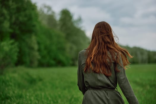 a woman with beautiful, well-groomed jumpy hair developing in the wind stands in a field. High quality photo
