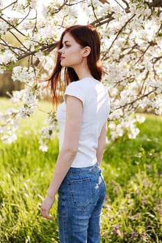 Beautiful young woman near blooming tree on spring day. High quality photo