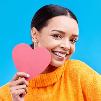 Paper heart, love and portrait of happy woman in studio, blue background and romantic sign. Female model, emoji shape and smile for care, support and thank you for kindness, valentines day or emotion.