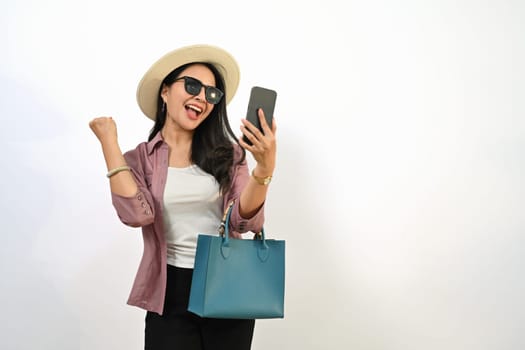 Excited female traveler looking mobile phone with good news or buying plane tickets on discount.