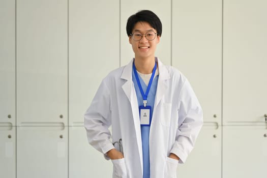 Cheerful young doctor in white coat with stethoscope posing and smiling at camera. Healthcare and medical concept.
