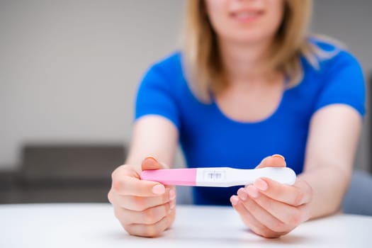 Attractive young woman holding a positive pregnancy test. Expecting of baby