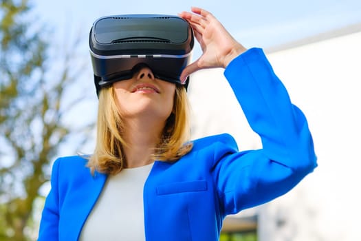 Smiling woman in vr glasses experiencing augmented reality in front of a business center. Futuristic future in the metaverse world.