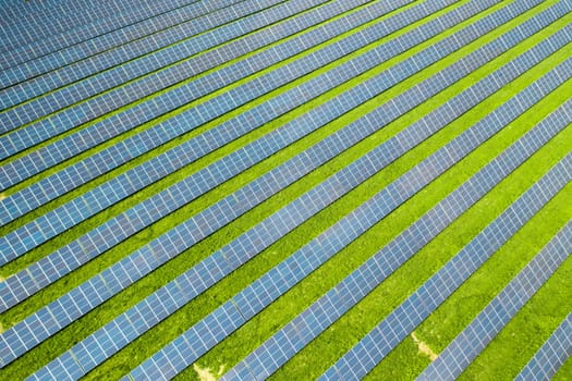 Long rows of sun panels built on green field. Innovative photovoltaic solar cells provide alternative energy at station aerial view