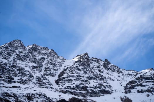 white wispy clouds moving over snow covered rocky himalaya mountains in spiti valley on the way to leh in manali himachal pradesh showing popular tourist place in India