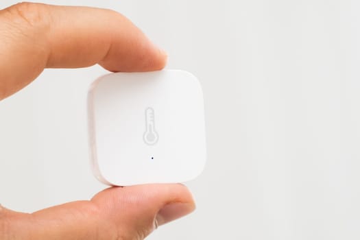 Aqara Smart Home Temperature Sensor in mans hand on the white background.