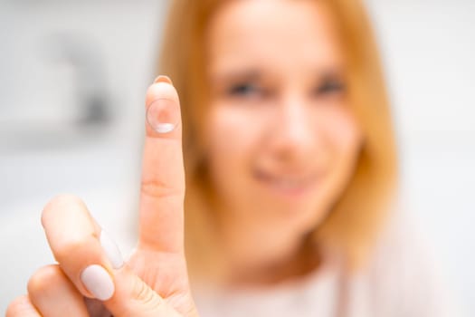Woman holding a contact lens on her finger. A smiling woman uses contact lenses for improvement in vision or changes in eye color