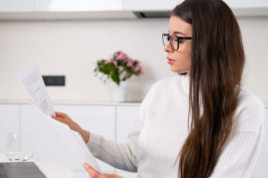 Woman with eye glasses working with documents and planning expenses. Businesswoman develops her startup.