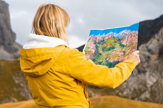 Back side of traveler woman searching the right way on the map in mountains, traveling and lifestyle concept.