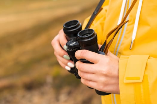 Close up binoculars in woman hands for looking in distance . Travel concept.