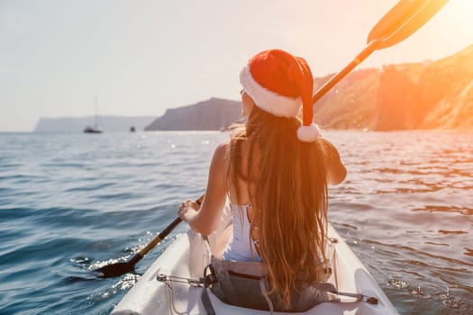 Woman in kayak back view. Happy young woman with long hair floating in transparent kayak on the crystal clear sea. Summer holiday vacation and cheerful female people relaxing having fun on the boat