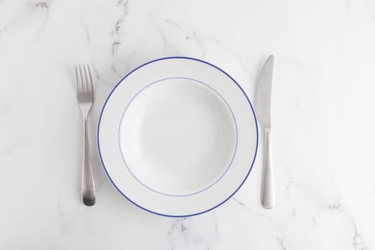 Empty white soup plate with blue stripe top view on a white background
