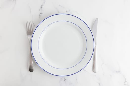 Empty white dinner plate with blue stripe top view on a white background
