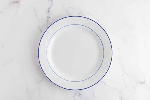 Empty white dinner plate with blue stripe top view on a white background