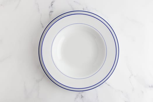 Empty white dinner plate with blue stripe top view on a white background