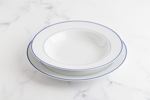 Empty white soup plate with blue stripe on a white background