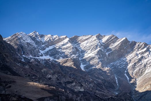 rocky himalayan peaks with snow covering the top against the blue sky showing the beauty of leh ladakh spiti valley in India