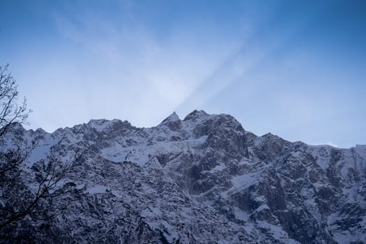 beautiful light rays coming from sunset behind snow covered peaks near atal tunnel lahul spiti leh ladakh in India