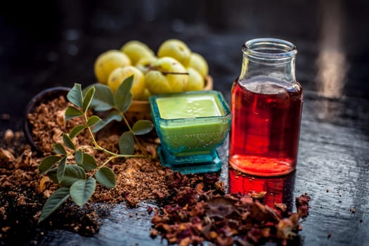 Close-up of ingredients of treatment for oily skin on a wooden surface i.e. amla powder with some raw organic rose water in a glass bowl.